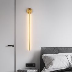 a bed sitting next to a white wall with a light on it's side