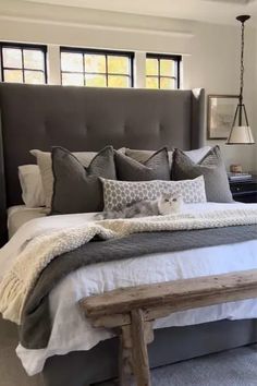 a large bed sitting in a bedroom next to a window with lots of pillows on top of it