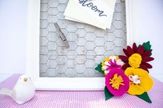 a photo frame with flowers and a bird on the table next to it that says mom