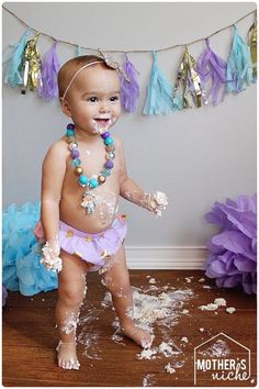 a baby is covered in cake and sprinkles while standing on the floor