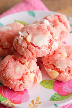 pink cookies with white frosting on a floral print plate, ready to be eaten