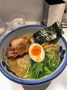 a bowl of ramen with an egg on top and some greens in the middle