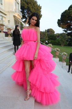 a woman in a pink dress standing on some steps