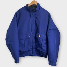 Carhartt Vintage Blue Nylon Workshield Blizzard Jacket Men’s Size Large Quilted Lining 100% Nylon Full Zip + Snap Button Closure J71 Cob //Approximate Measurements// Pit To Pit: 26” Length: 28” Great Used Condition. No Holes, No Stains. Blue Windproof Outerwear For Streetwear, Blue Windbreaker With Pockets For Cold Weather, Blue Fleece-lined Windbreaker For Streetwear, Blue Insulated Hooded Outerwear, Blue Insulated Outerwear For Cold Weather, Blue Utility Outerwear For Winter, Utility Blue Outerwear For Winter, Insulated Blue Outerwear For Outdoor Activities, Carhartt Vintage