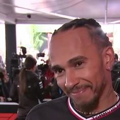 a man with dreadlocks is smiling at the camera while wearing a black shirt