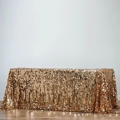 a gold sequin tablecloth on a wooden floor in front of a white wall