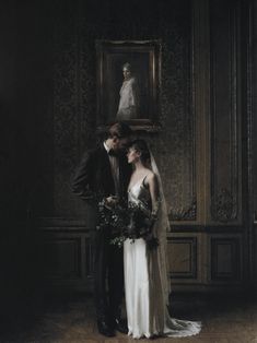 a bride and groom standing in front of a portrait