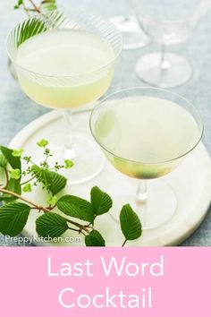 two glasses filled with white wine sitting on top of a table next to each other