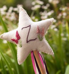 a white star shaped object with pink flowers on it's tip, sitting in the grass