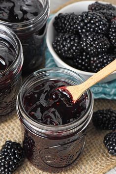 blackberries in jars with a wooden spoon next to them