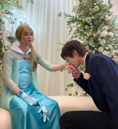 a man kneeling down next to a woman in a blue dress