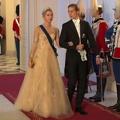 a man and woman in formal dress standing next to each other on a red carpet