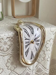 an ornate clock is sitting on top of a lace tablecloth in front of a mirror