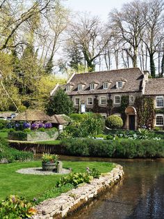 a large house sitting on top of a lush green field next to a small river