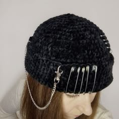 a woman wearing a black knitted hat with metal spikes and chains attached to it