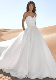 a woman in a white dress standing on top of a sand dune with the caption pronovia's