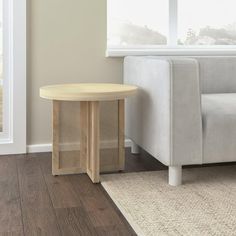 a white couch sitting next to a wooden table on top of a hard wood floor