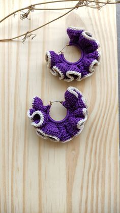 two purple crocheted baby shoes sitting on top of a wooden table next to twigs