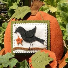 an orange pumpkin with a black bird on it sitting in the middle of green leaves