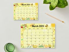 two calendars with flowers and plants on them next to a cup of green tea