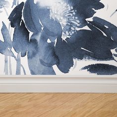 a blue and white flower painting on the wall next to a wooden floor in front of a framed photograph