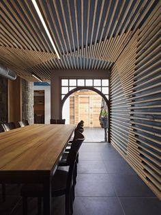 a large wooden table sitting under a window next to a wall covered in wood slats