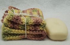 three crocheted dishcloths and a soap bar on a white surface