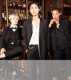 three women standing next to each other in front of a bar