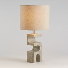 a lamp that is sitting on top of a stone block with a light shade over it