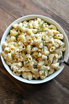 a white bowl filled with macaroni and cheese on top of a wooden table