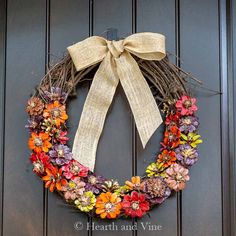 a wreath with flowers and a bow hanging on the front door to give it a rustic feel