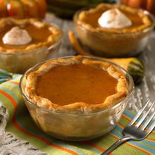 three pies sitting on top of a table covered in frosting and pumpkins