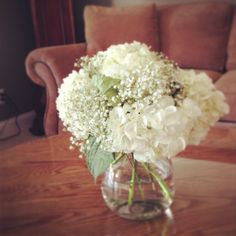 a vase filled with white flowers sitting on top of a table next to a couch