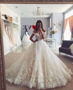 a woman standing in front of a mirror wearing a wedding dress