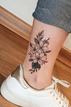 a black and white flower tattoo on the ankle