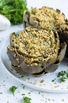 some artichokes are sitting on a plate with parsley sprinkled