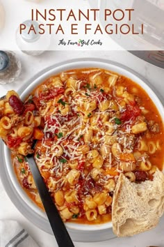 a white bowl filled with pasta and sauce on top of a table next to bread