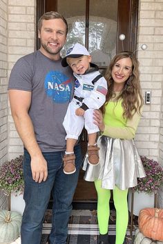 a man and woman standing in front of a door with a child on their lap