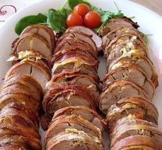 a white plate topped with sliced up meat and veggies next to tomatos