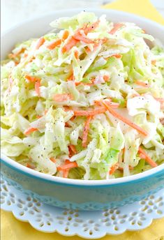 a bowl filled with coleslaw and carrots on top of a doily