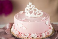 a pink cake decorated with hearts and a tiara on top