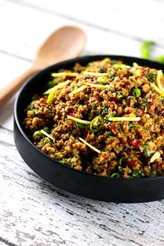 a black bowl filled with meat and vegetables