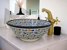 a bowl shaped sink on top of a white counter next to a faucet