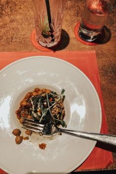 a white plate topped with food on top of a red place mat next to two glasses