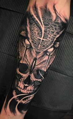 a man's arm with a black and grey tattoo design on it, including a skull