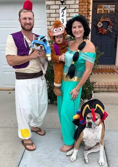 two men and a woman in costumes pose for a photo with a dog on the front porch