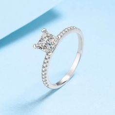 a princess cut diamond ring on a blue background