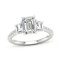 an emerald cut diamond engagement ring with diamonds on the band and shoulders, set in 18k white gold