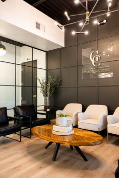 a living room with chairs and a table in front of a glass wall that has a logo on it