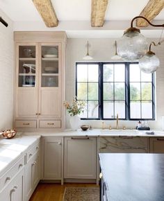 a kitchen with white cabinets and marble counter tops